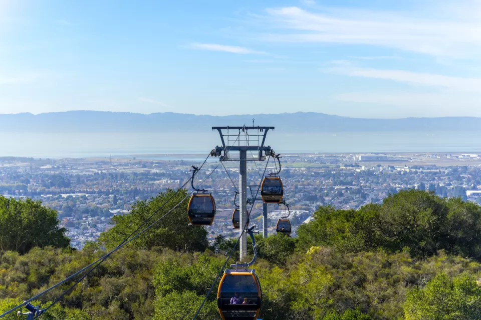 View of aerial tram cars at Oakland Zoo with Oakland, California neighborhoods in background.